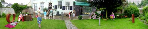 A panoramic spread of the museum and all the groups present in the back garden.